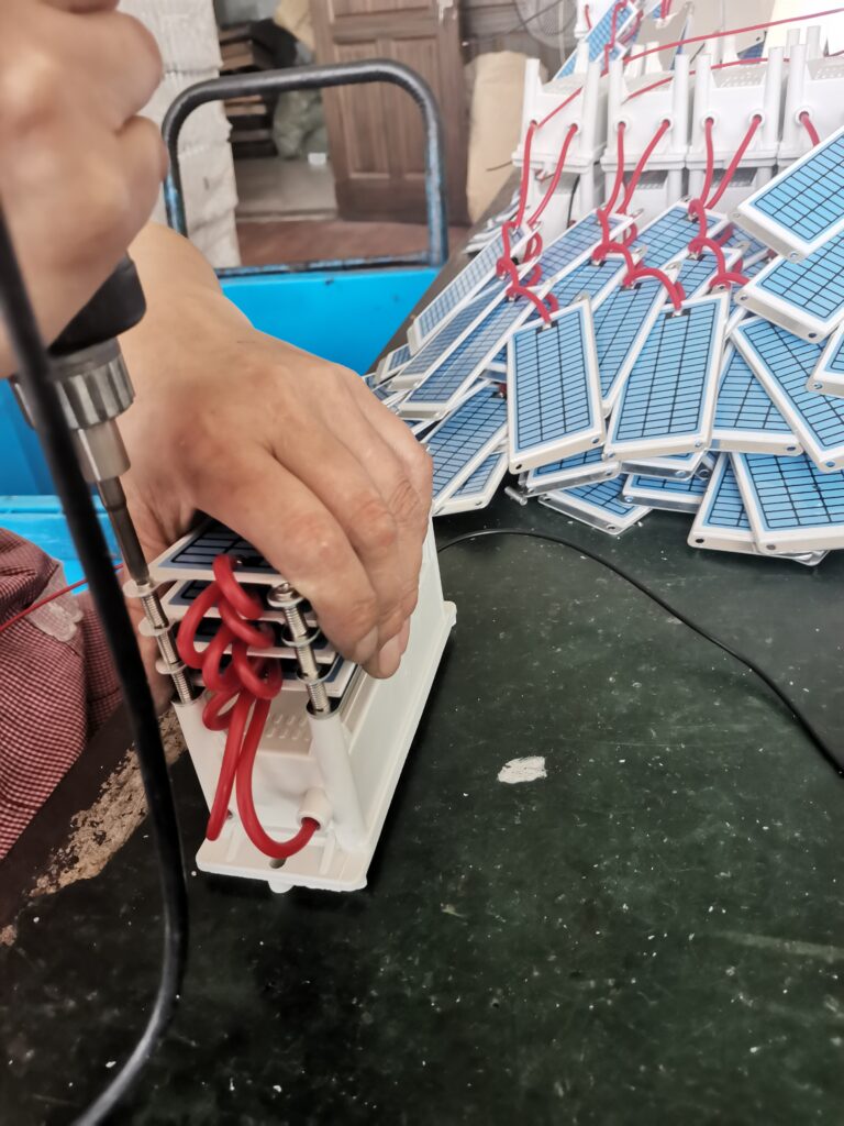 工位上用螺丝固定陶瓷放电片与电源组件的近景，2022年生产照片